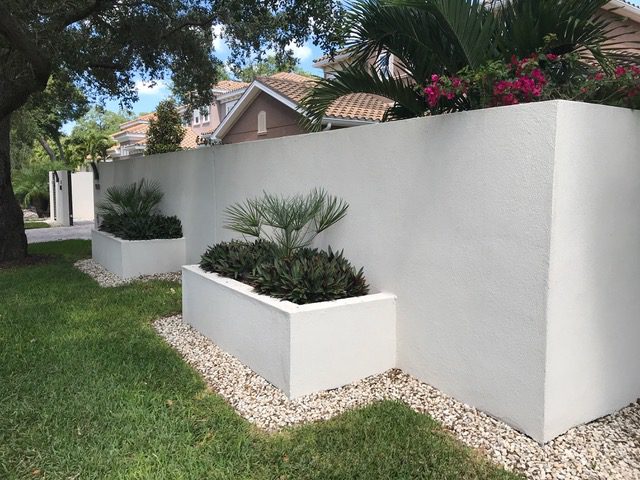 White garden wall with greenery and flowers.