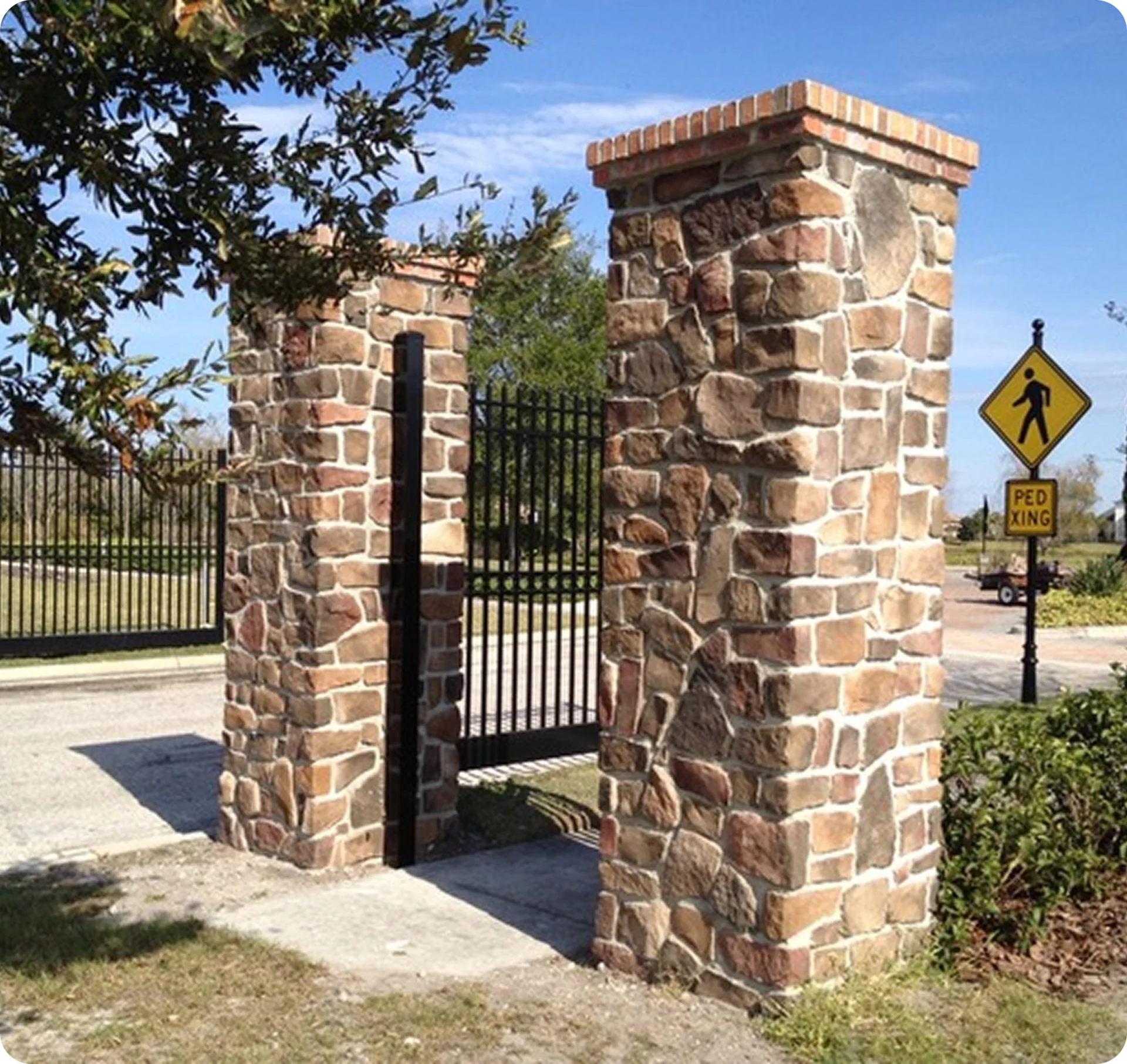 Stone pillars with pedestrian crossing sign nearby.