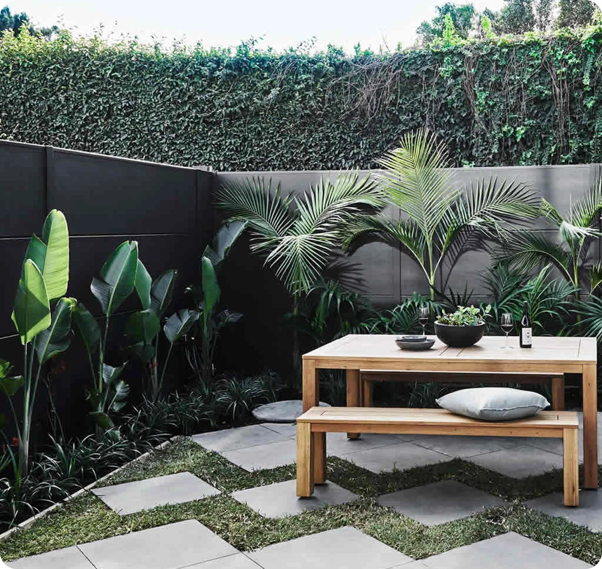 Modern patio with plants and wooden furniture.